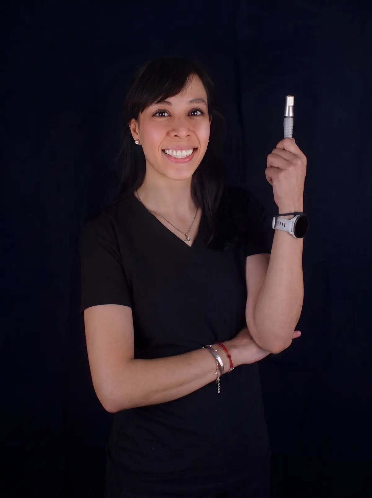 Dra. Jessica García, periodoncista, sonriendo y sosteniendo un implante dental
